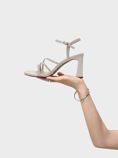 En hand som håller upp en klacksko med remmar