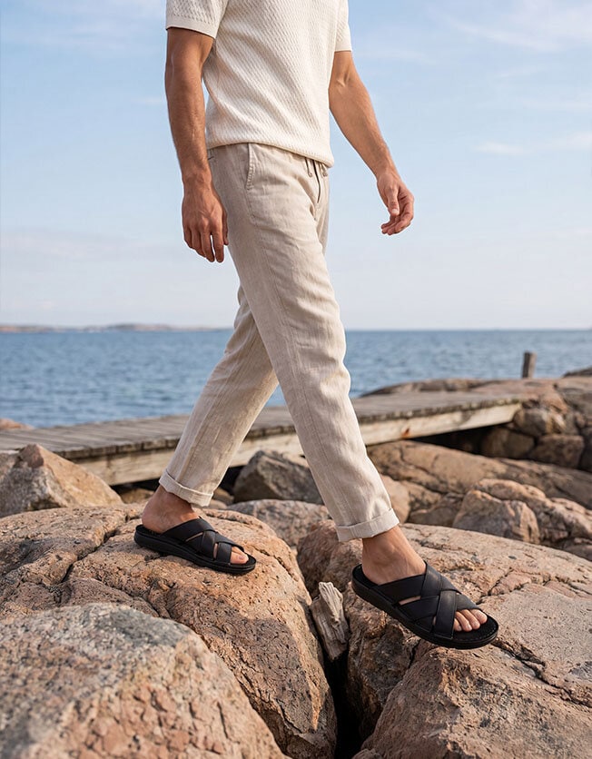 Manliga ben i beige byxor och svarta remsandaler i skinn 549kr
