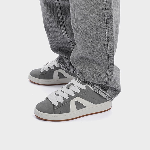 Benbild med mörka jeans och gråa sneakers med vita mönster